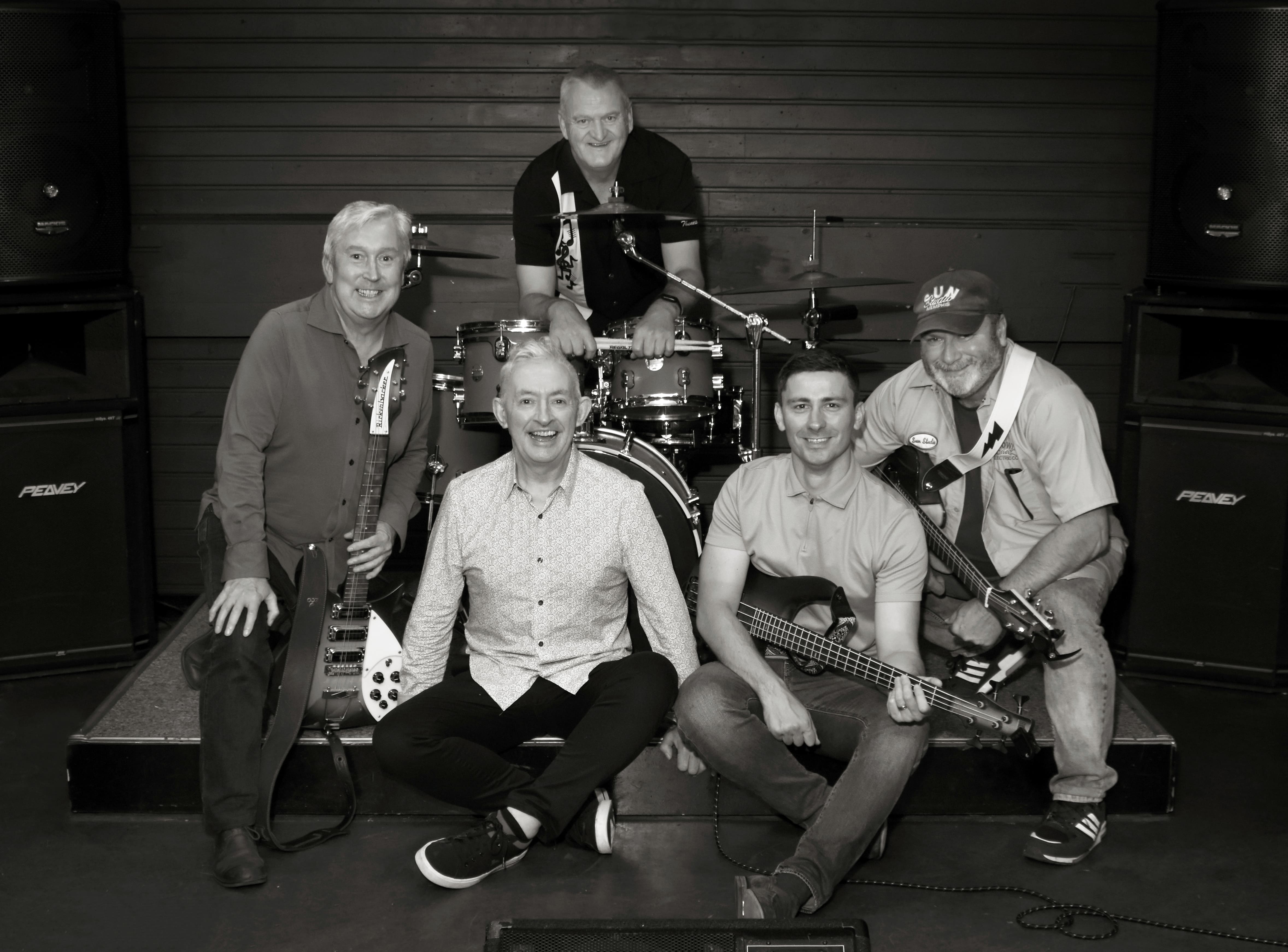 The five members of Creek Crosby with their instruments on a small stage